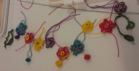 individual crocheted flowers, buds, leaves and tendrils